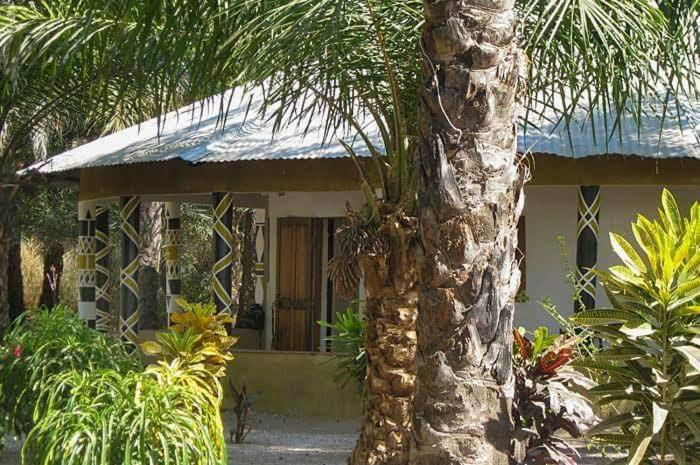 a house with a palm tree in front of it at Campement Sindéye in Abémé
