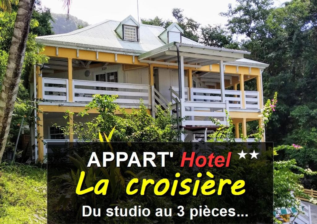 Gourbeyre的住宿－Appart'hotel La croisière，黄色房子前面有标志