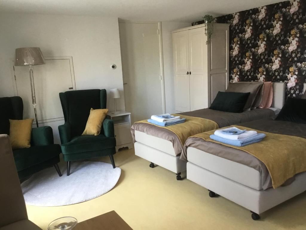 een woonkamer met 2 bedden en 2 stoelen bij B & B Rosamie in Vlissingen