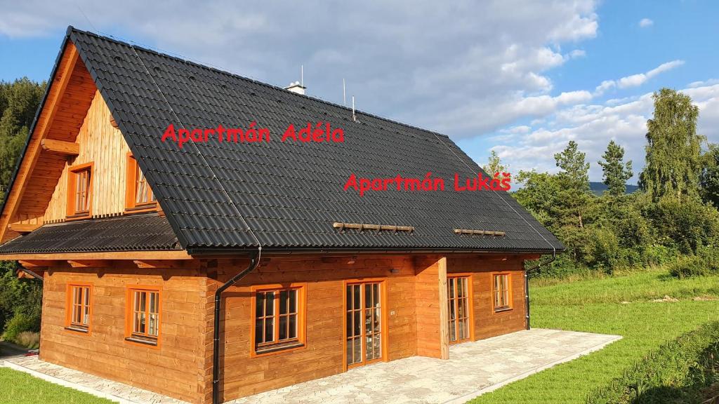 a large wooden building with a black roof at Apartmány Orlice in Červená Voda