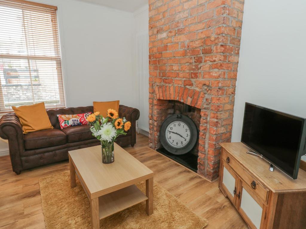 een woonkamer met een open haard, een bank en een tv bij Laridae in Whitby