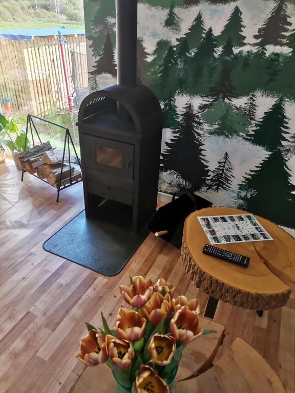 a stove in a living room with a table and a bowl of fruit at Bieszczadzkie BOHO stodoły z jacuzzi i sauna na wyłączność in Myczkowce