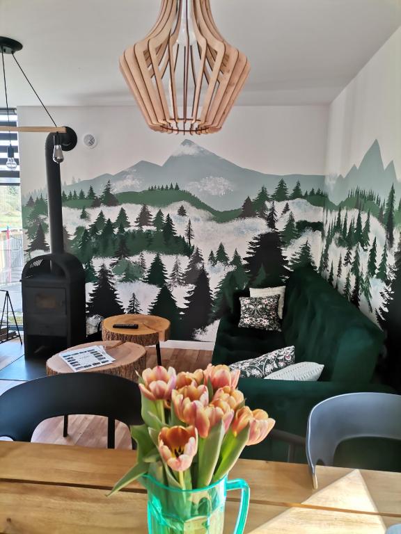 a living room with a couch and a table with flowers at Bieszczadzkie BOHO stodoły z jacuzzi i sauna na wyłączność in Myczkowce