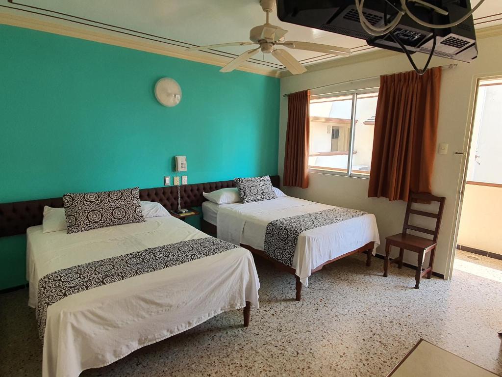 Cette chambre comprend 2 lits et un mur vert. dans l'établissement Hotel Atlantico a 150 mts de Playa Martí, à Veracruz