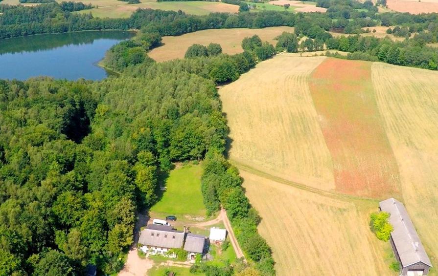 una vista aérea de una casa en un campo junto a un lago en Gospodarstwo Agroturystyczne LOBELIA, en Pomysk Wielki