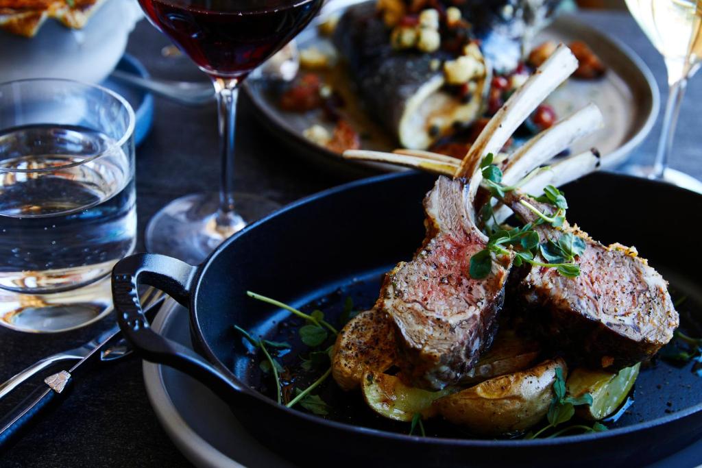 a plate of food with meat and a glass of wine at Kimpton - Armory Hotel Bozeman, an IHG Hotel in Bozeman