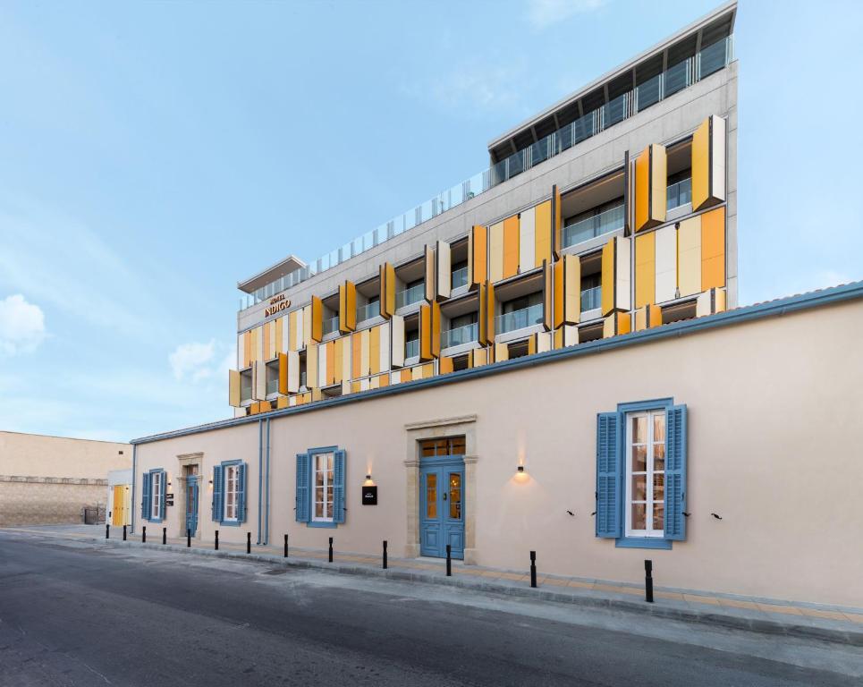 a building with blue and yellow windows on a street at Hotel Indigo Larnaca - Adults Only, an IHG Hotel in Larnaca