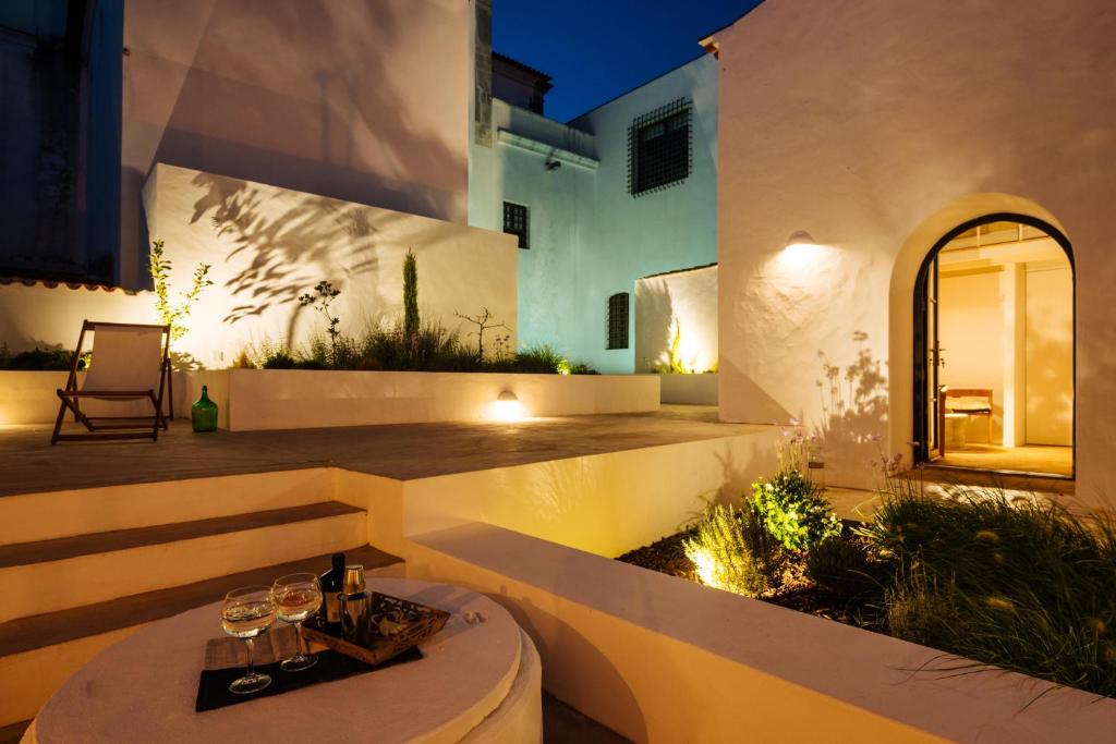 un patio con una mesa con copas de vino. en Aljana Guest House Beja en Beja