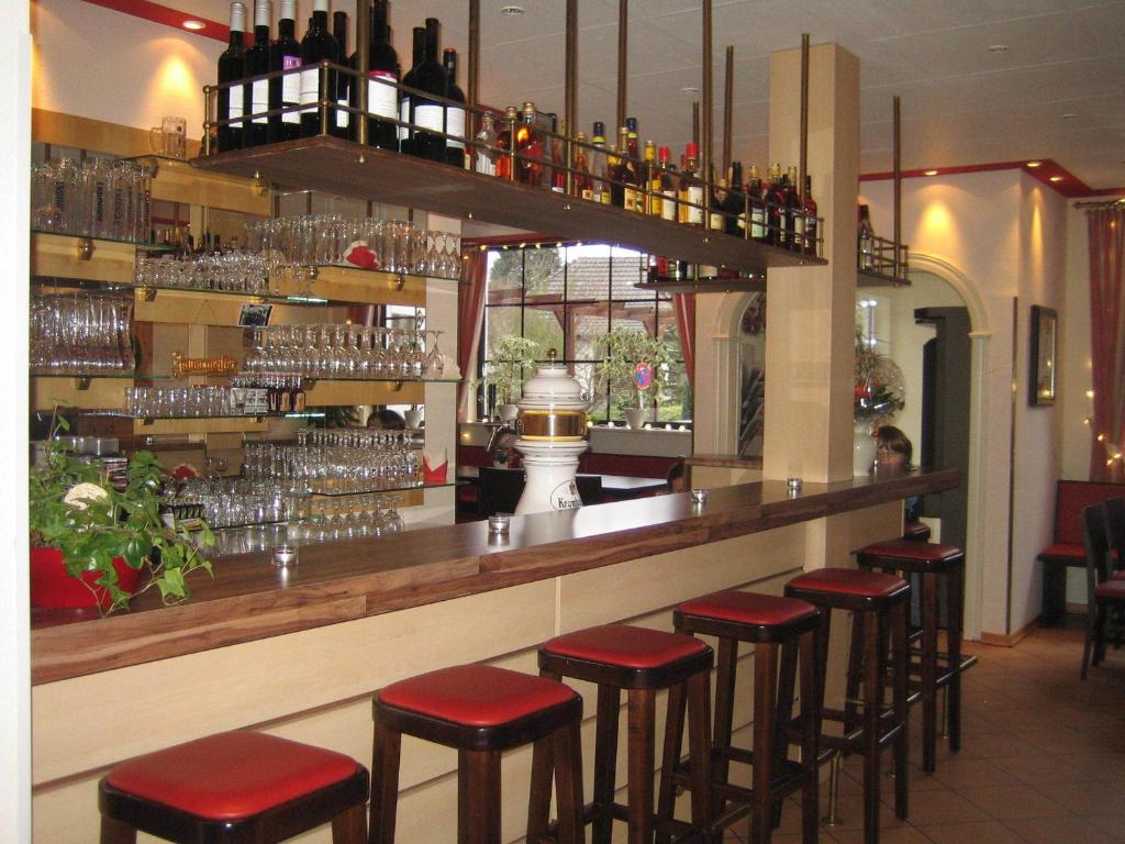 Hotel & Restaurant Jägerstuben في Ritterhude: بار به مقاعد حمراء في مطعم