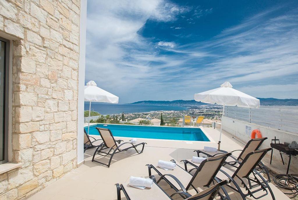 a patio with chairs and a swimming pool at Villa Tavrou Dyo - Luxury 3 Bedroom Latchi Villa with Private Pool - Stunning Sea Views in Neo Chorio