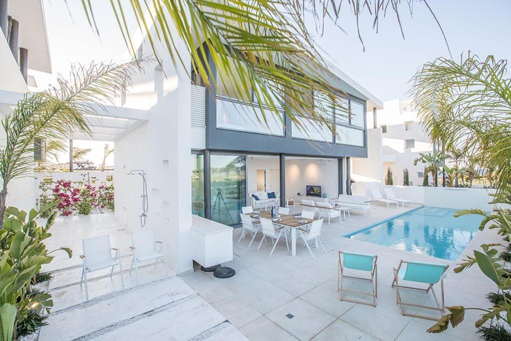 een huis met een zwembad en een tafel en stoelen bij Villa Limni Enas - Luxury and Contemporary 3 Bedroom Kapparis Villa with Sea views in Paralimni