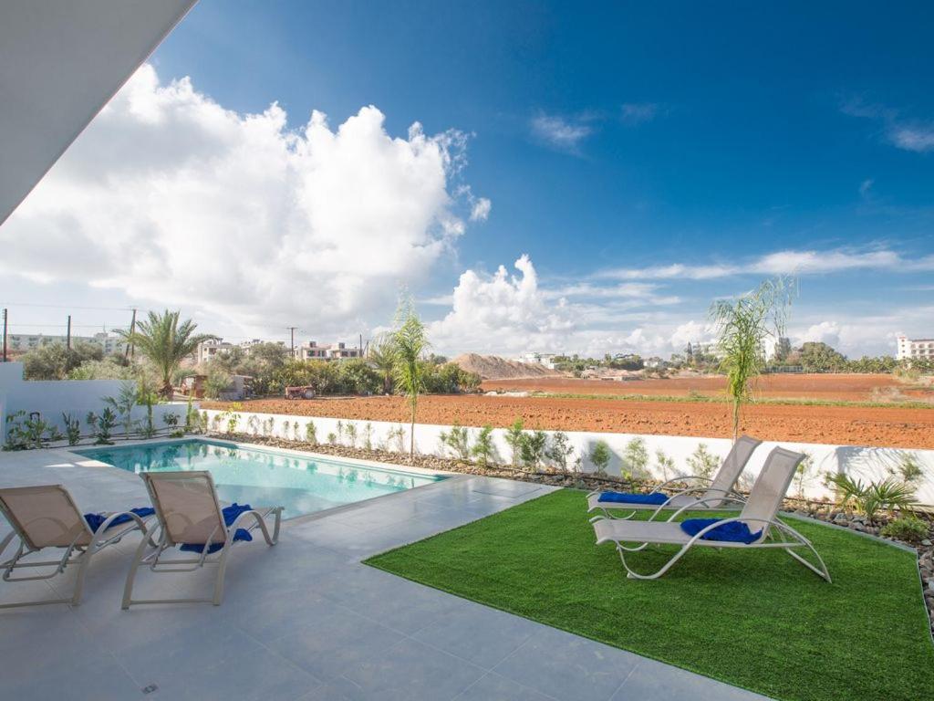 eine Terrasse mit Stühlen und einem Pool in der Unterkunft Villa Panemorfi - Luxury Brand New 3 Bedroom Protaras Villa with Private Pool and Sea Views in Protaras