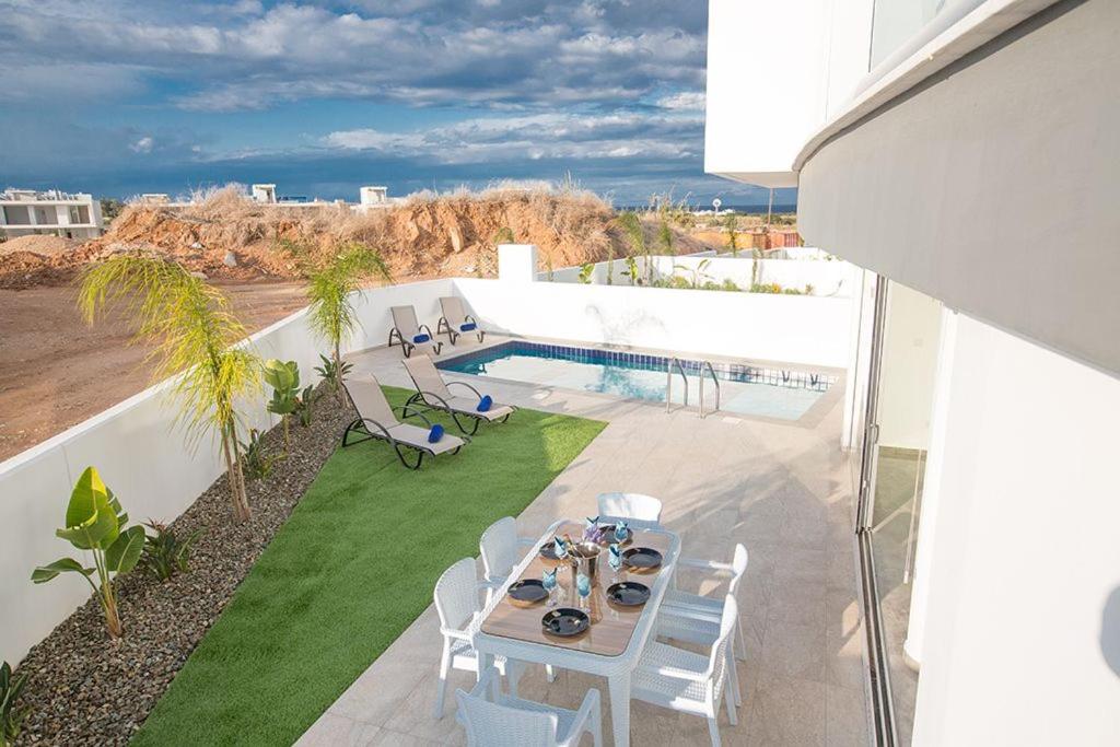 eine Terrasse mit einem Tisch und Stühlen sowie einem Pool in der Unterkunft Villa Olive Gold Luxury and Brand New 2BDR Protaras Villa with Private Pool in Protaras