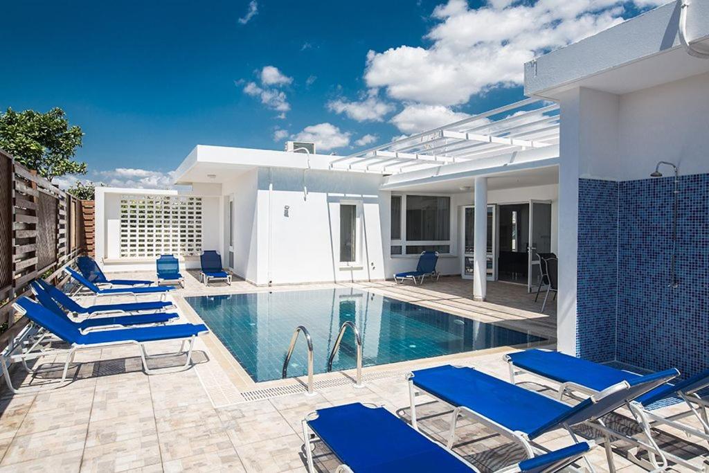 a swimming pool with blue chairs next to a house at Villa Mavris - Lovely 4 Bedroom Villa with Private Pool in Central Ayia Napa in Ayia Napa