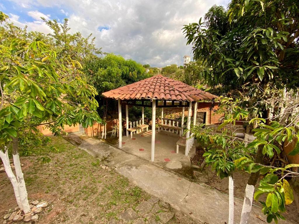 un pavillon avec une table et des bancs dans un jardin dans l'établissement Villa Claudia - apartamento cómodo y tranquilo, à El Colegio