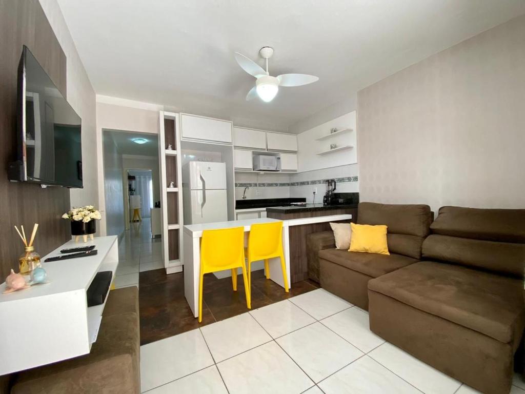 ein Wohnzimmer mit einem Sofa, einem Tisch und gelben Stühlen in der Unterkunft Apto 2 dom e 1 quadra do mar edifício Vila Velha Capão da Canoa in Capão da Canoa