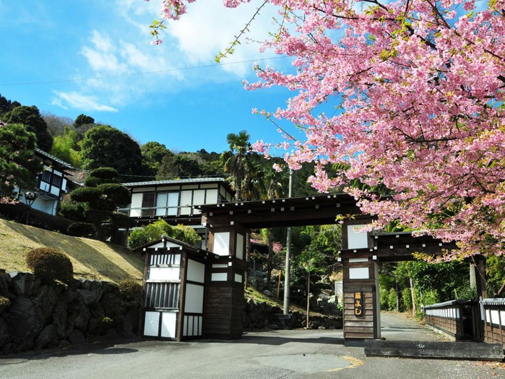 a gate with aakura tree in front of a building at Yokohama Fujiyoshi Izuten in Ito