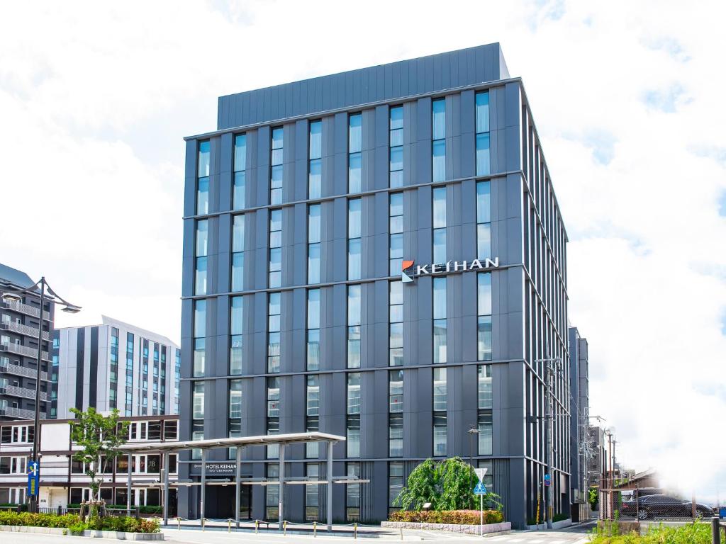 un edificio de cristal alto con un cartel de akhtar. en Hotel Keihan Kyoto Ekiminami en Kyoto