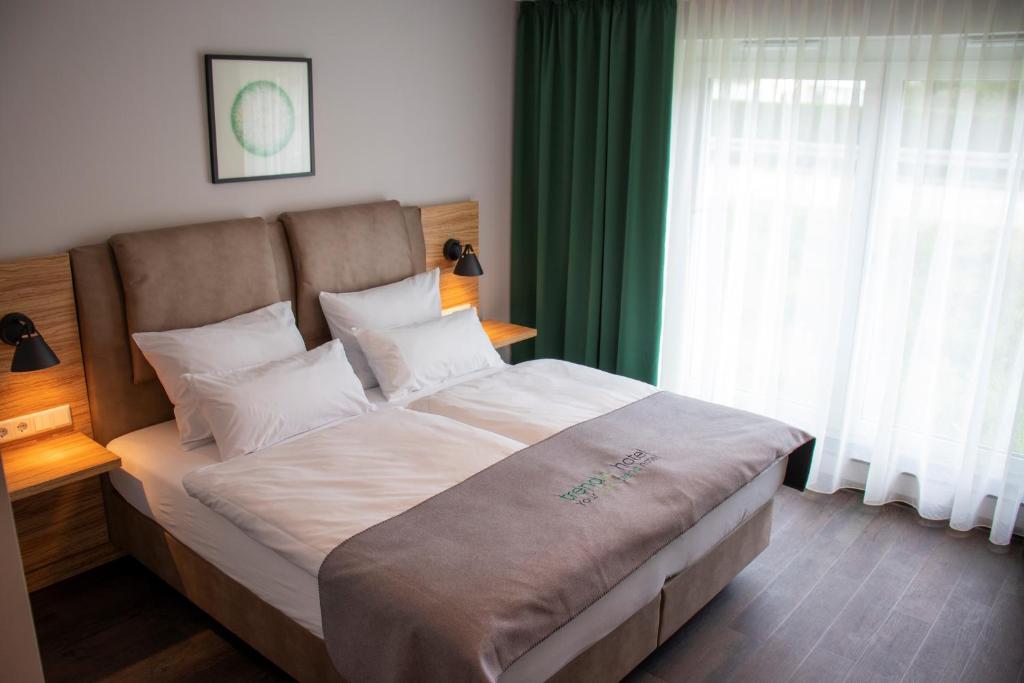 1 dormitorio con 1 cama grande y cortinas verdes en Trendic Hotel en Marktoberdorf