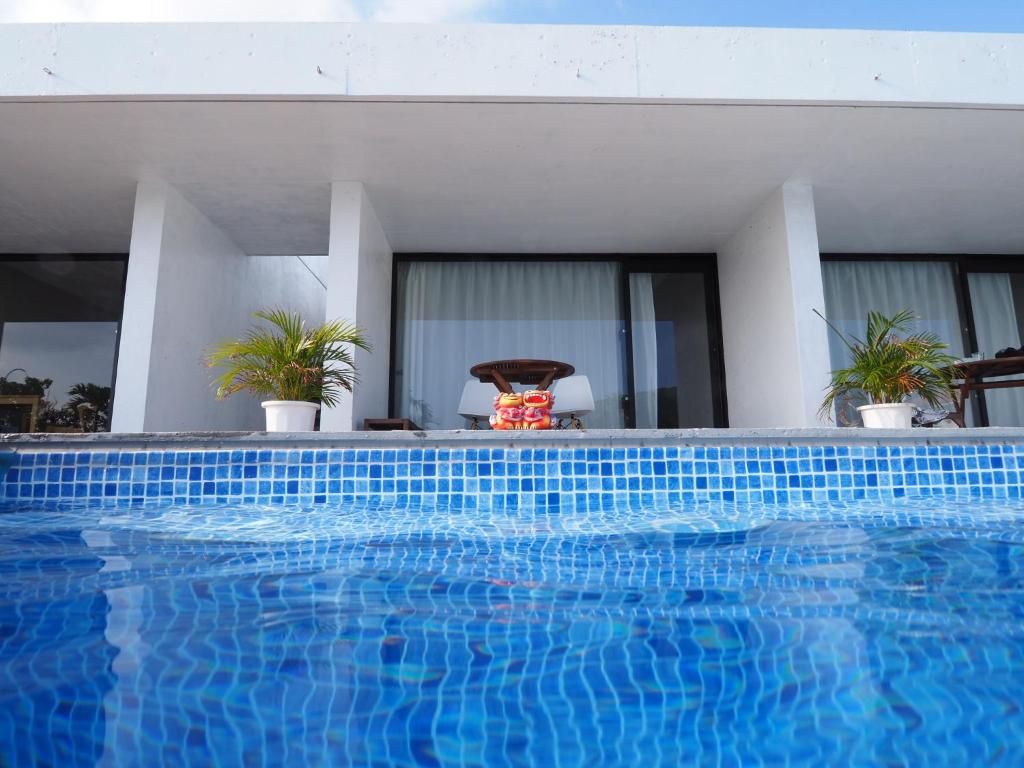 una piscina azul frente a una casa en Blue Suites Hanamuro en Zamami