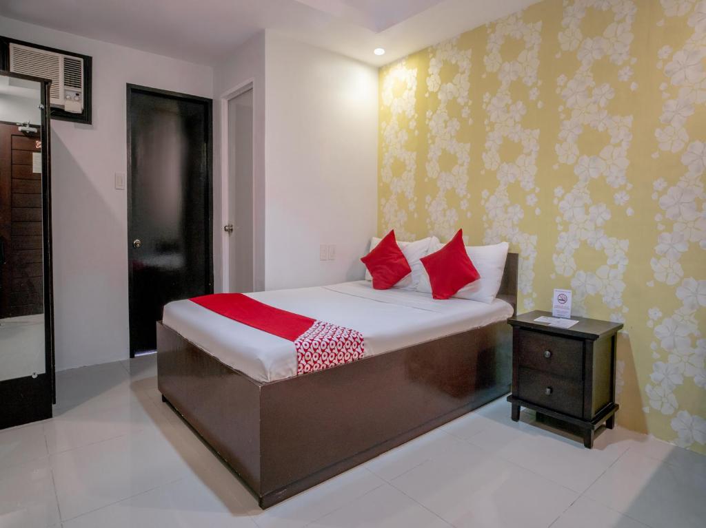 a bedroom with a bed with red pillows at OYO 697 Obrero Suites in Davao City