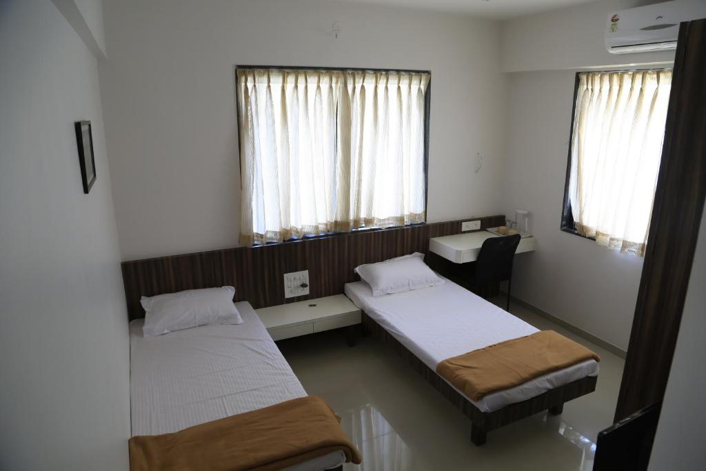 a hospital room with two beds and a desk at Aashiyana Inn in Nashik