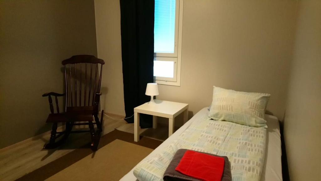 a bedroom with a bed and a chair and a window at Apartment Pistoolintie in Pyhäjoki