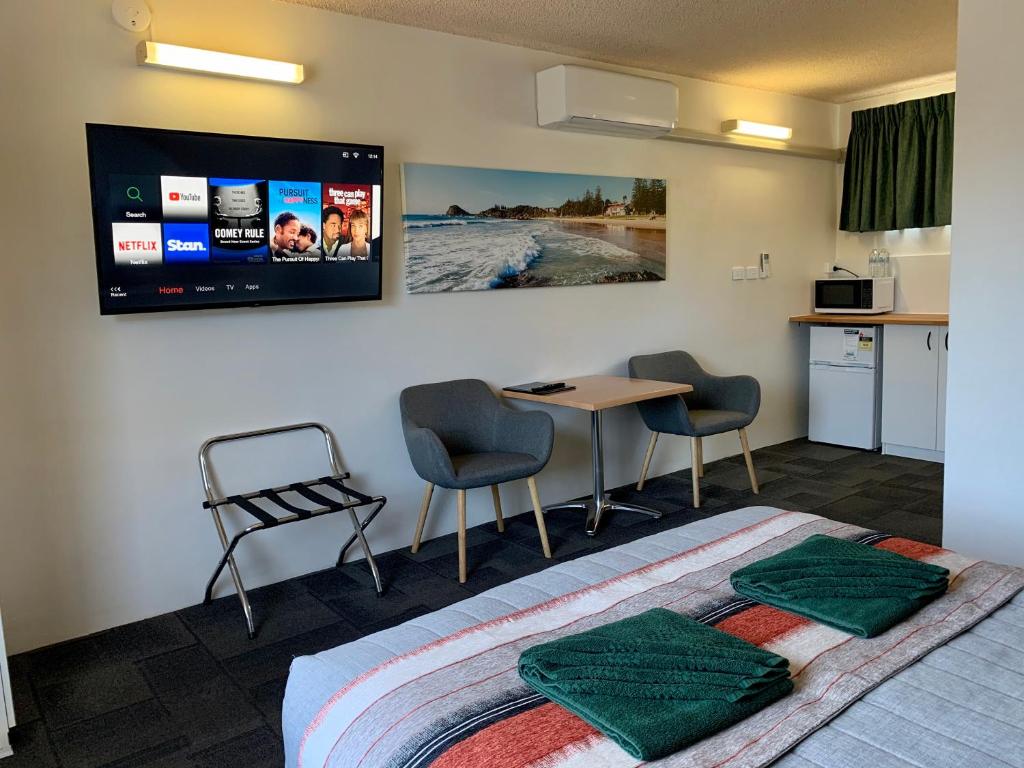 a room with a bed and a table and a kitchen at Mariner Motel in Laurieton