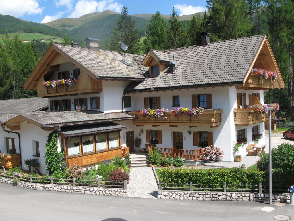 une grande maison blanche avec des fleurs sur les balcons dans l'établissement Appartements Barbara, à Sesto