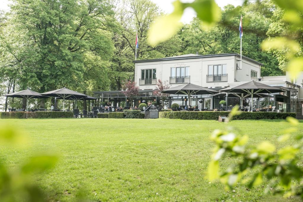 a white building with black umbrellas in a park at Hotel Restaurant De Wolfsberg in Groesbeek