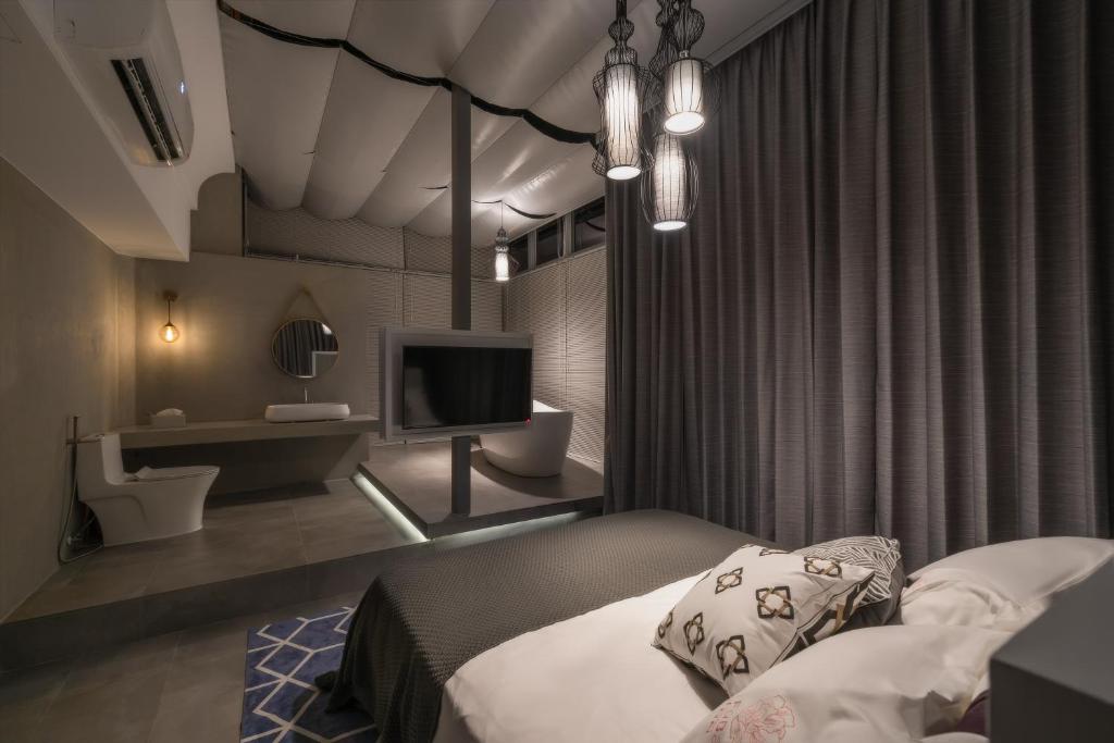 1 dormitorio con 1 cama y TV en una habitación en Kenting Fu Bao Inn, en Hengchun