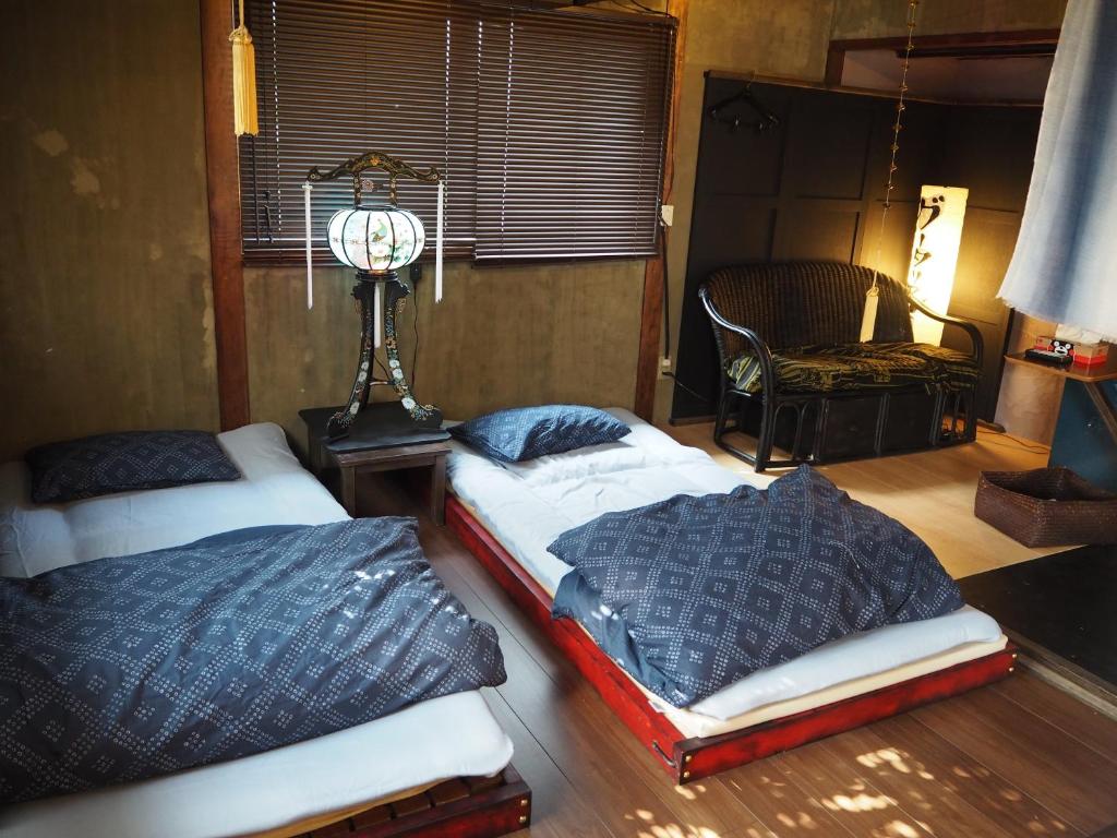 熊本市にある民泊カフェ Gootarianのランプと椅子付きの客室内のベッド2台