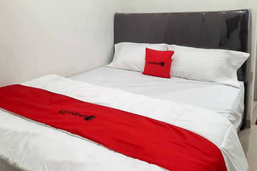 1 cama con manta roja y almohadas blancas en RedDoorz near Jalan Perintis Kemerdekaan Lampung, en Tanjungkarang