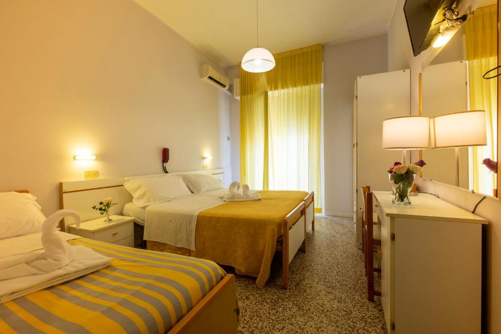 a hotel room with two beds and a mirror at Hotel Giumer in Rimini