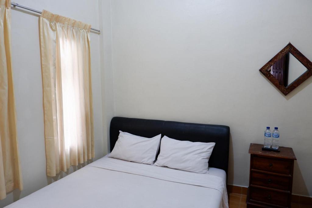 a bedroom with a bed with a black headboard and a window at Khresna Guest House Malioboro Mitra RedDoorz in Yogyakarta