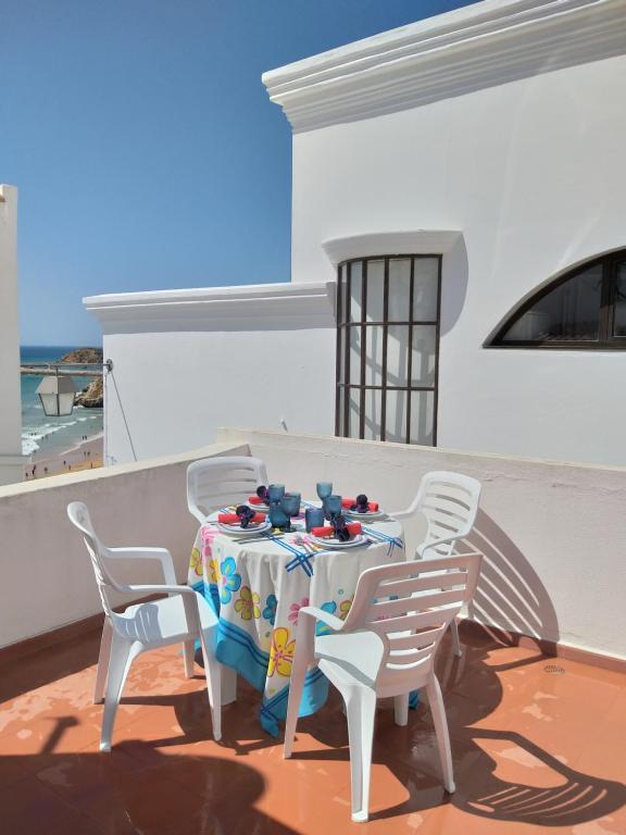 a table and chairs on a balcony with the ocean in the background at Casa do Avô in Albufeira
