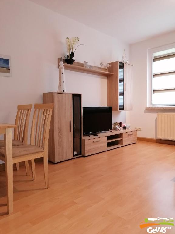 een woonkamer met een televisie en een tafel en stoelen bij Ferienwohnung Karl 54 in Gelenau