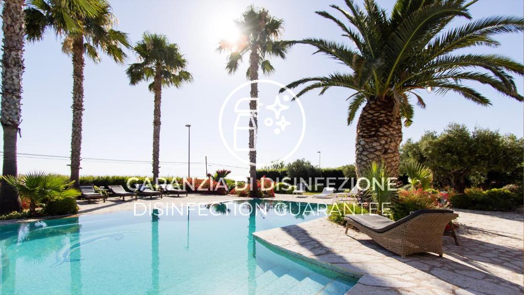 un complejo con piscina y palmeras en Visitsicilia Villa Cialoma, en Scopello