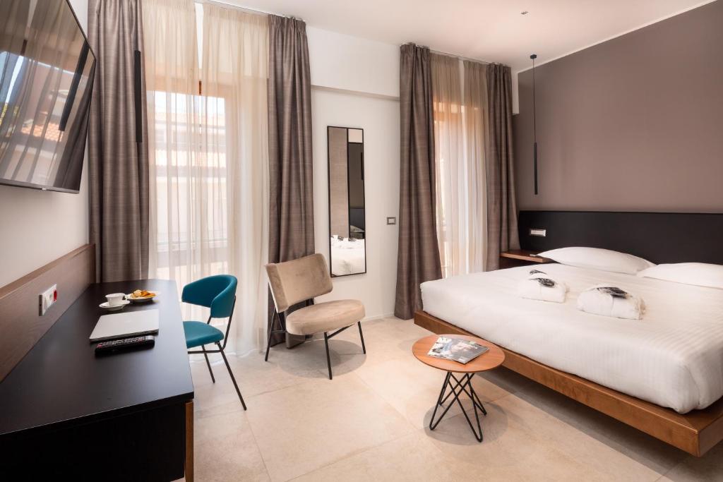 a hotel room with a bed, chair, desk and a television at The Corner Duomo Hotel in Milan