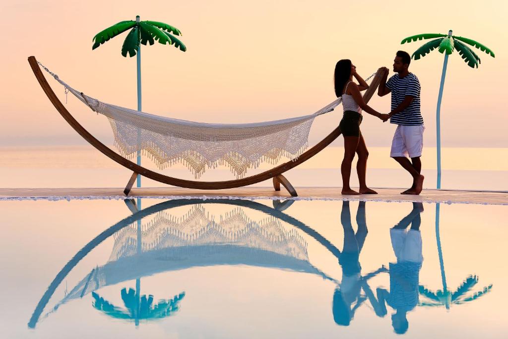 um casal ao lado de uma rede na praia em Alexandra Elegance Bridging Generations em Potos