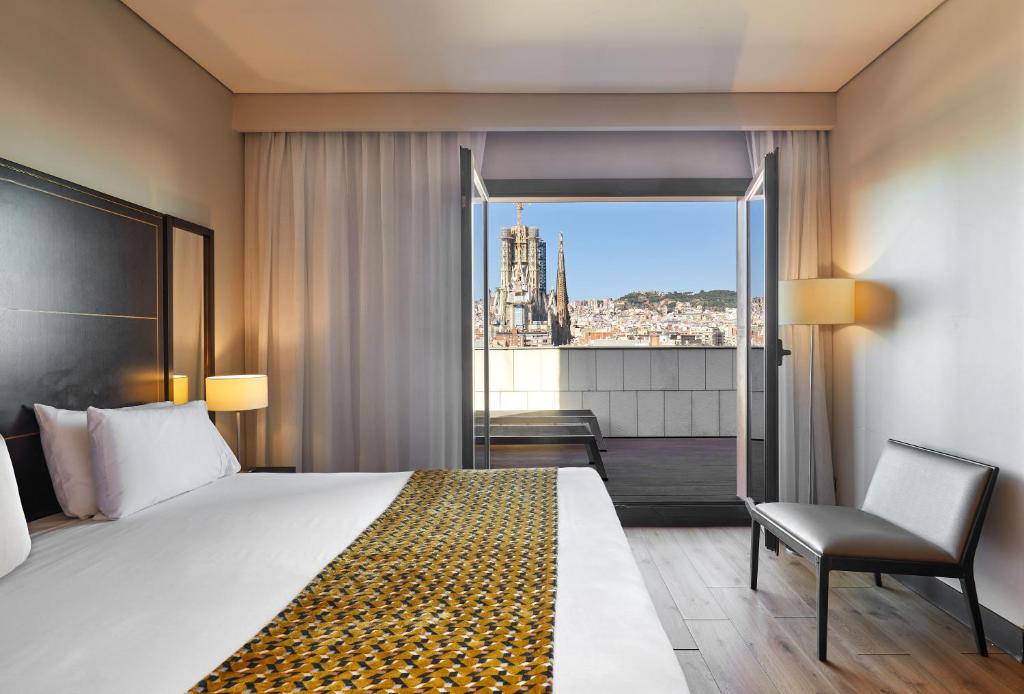 Pokój hotelowy z łóżkiem, krzesłem i oknem w obiekcie Eurostars Monumental w Barcelonie