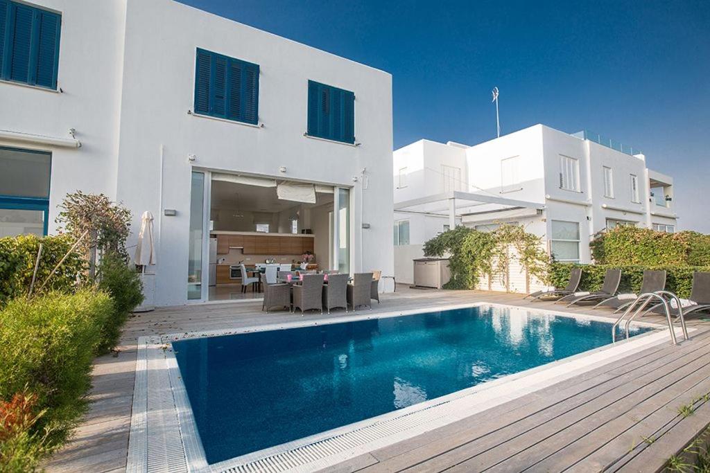 a swimming pool in front of a white house at Villa Fig Tree Bay FrontlineLuxury 4BDR Sea-front Protaras Villa with Pool and Amazing views in Protaras