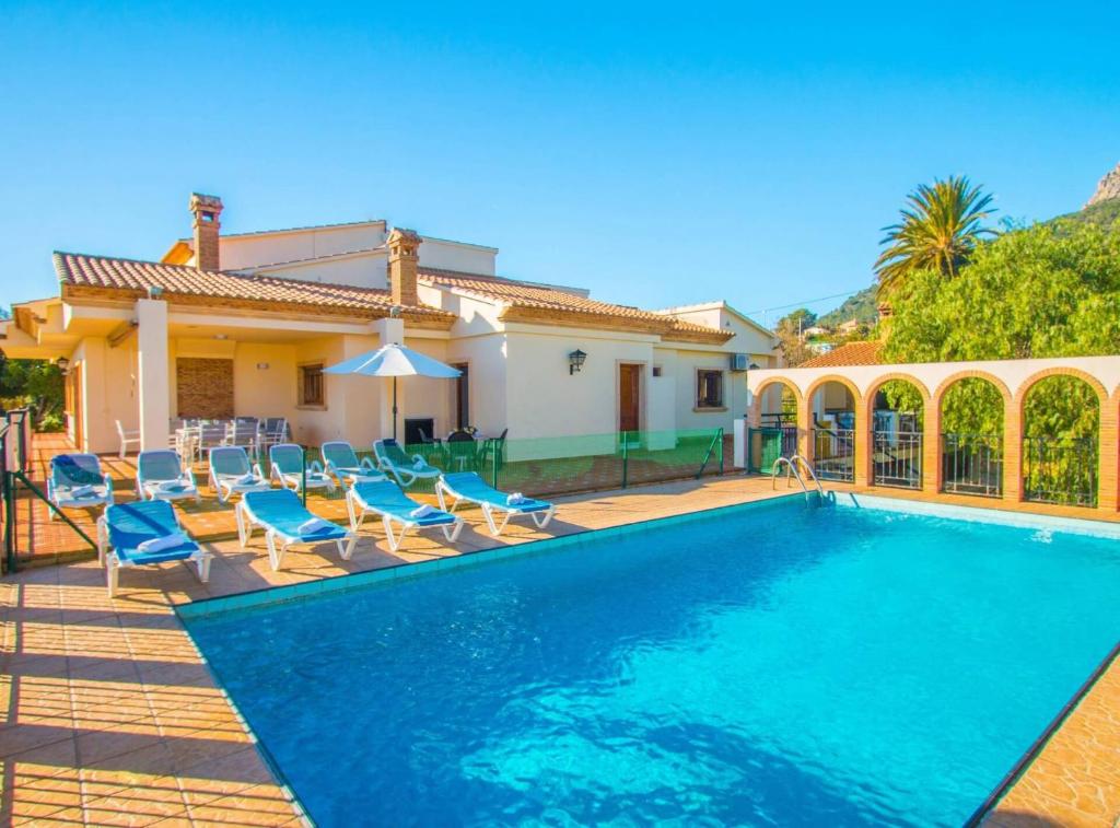 a swimming pool with chairs and a house at Villa Perles - Plusholidays in Calpe