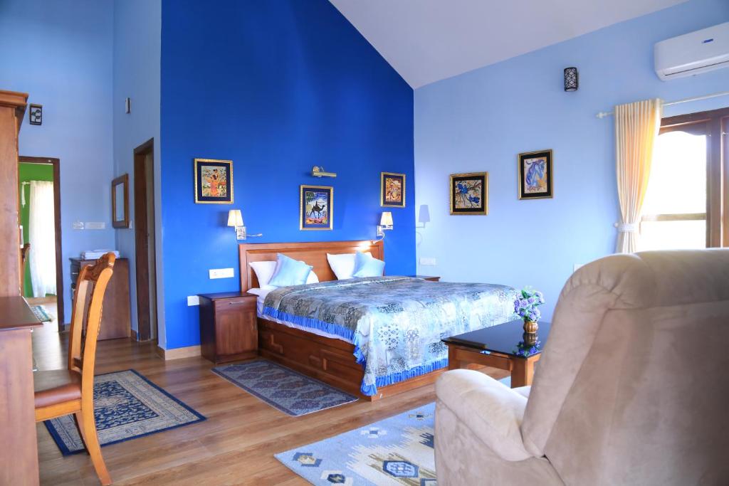 een blauwe slaapkamer met een bed en een stoel bij Room in Villa - Luxury cottages with beautiful mountain view in Anachal