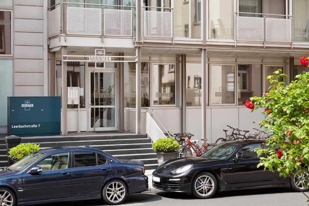 twee auto's geparkeerd voor een gebouw bij The Doorman Welle Frankfurt am Main in Frankfurt am Main