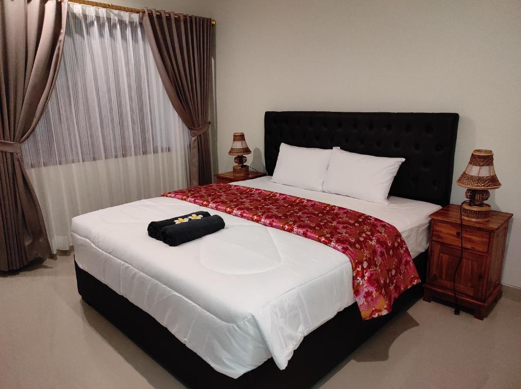 a bedroom with a large bed with a black headboard at Kubu Di-Kayla's in Sanur