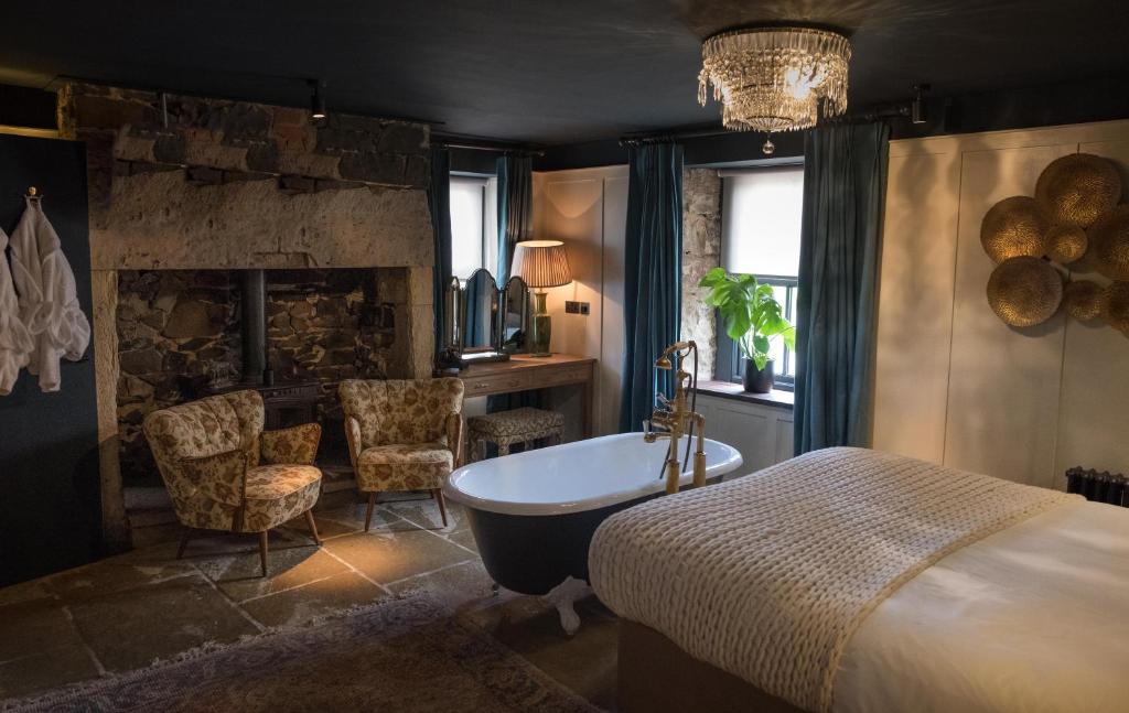 a bedroom with a bath tub and a fireplace at The Joiners Arms in Chathill