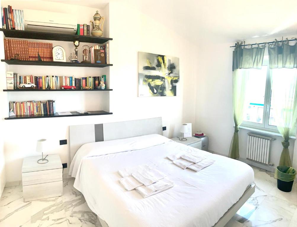 sypialnia z białym łóżkiem i półką na książki w obiekcie La Casa sui Tetti w Genui