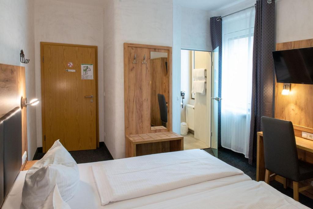 um quarto de hotel com uma cama, uma secretária e uma televisão em Hotel Fischertor em Augsburg