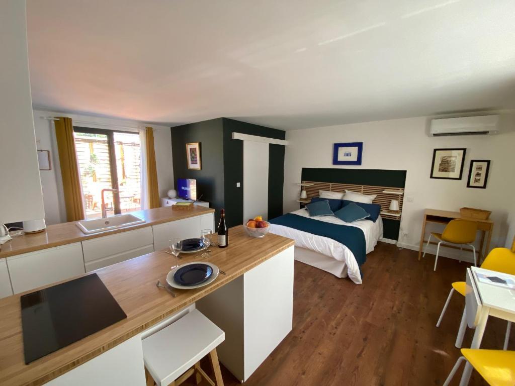 a bedroom with a bed and a kitchen with a counter at Les cèdres in Uzès